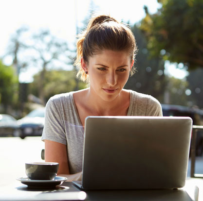 Junge Frau arbeitet an ihrem Laptop in einem Cafe